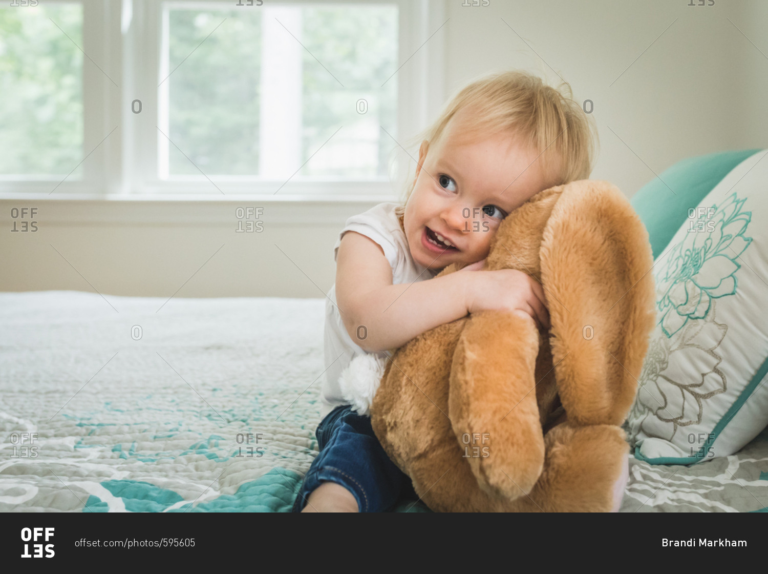 Baby girl hugging stuffed animal on bed