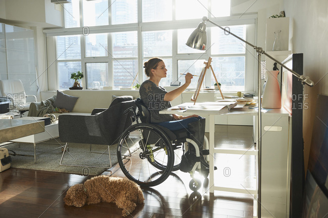 Caucasian woman in wheelchair painting on easel