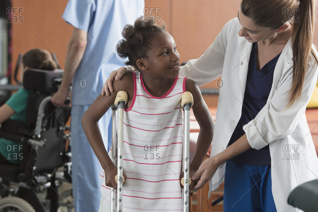 Doctor assisting girl with crutches