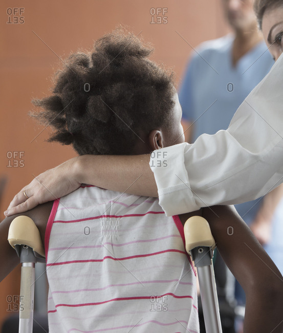 Doctor comforting girl with crutches