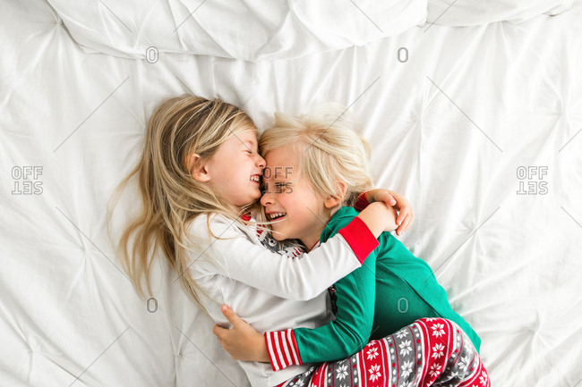Little boy and little girl have fun in bedroom wearing Christmas pajamas