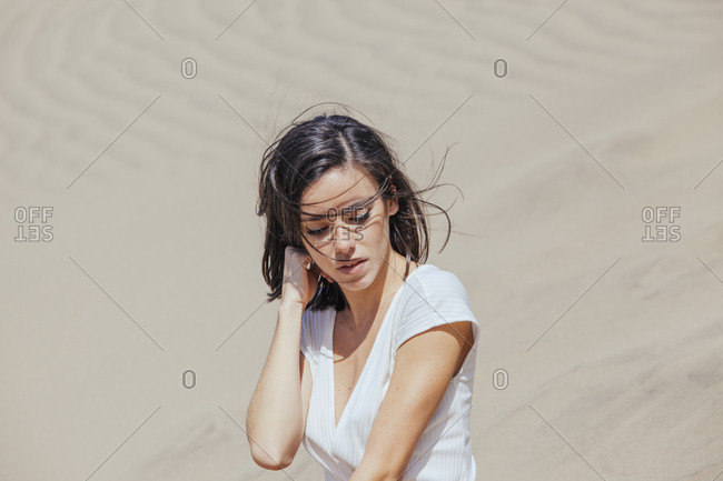 Beautiful woman in white t-shirt posing sensually on background of sands of desert.