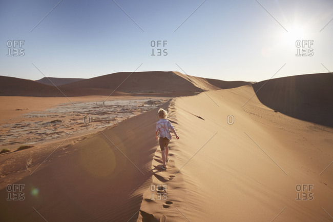 Boy walking on sand dune, Namib Naukluft National Park, Namib Desert, Sossusvlei, Dead Vlei, Africa