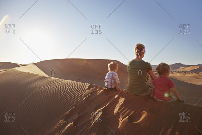 Mother and sons sitting on sand dune, Namib Naukluft National Park, Namib Desert, Sossusvlei, Dead Vlei, Africa