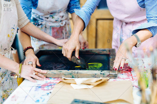 Three women working on silk screen print in creative studio