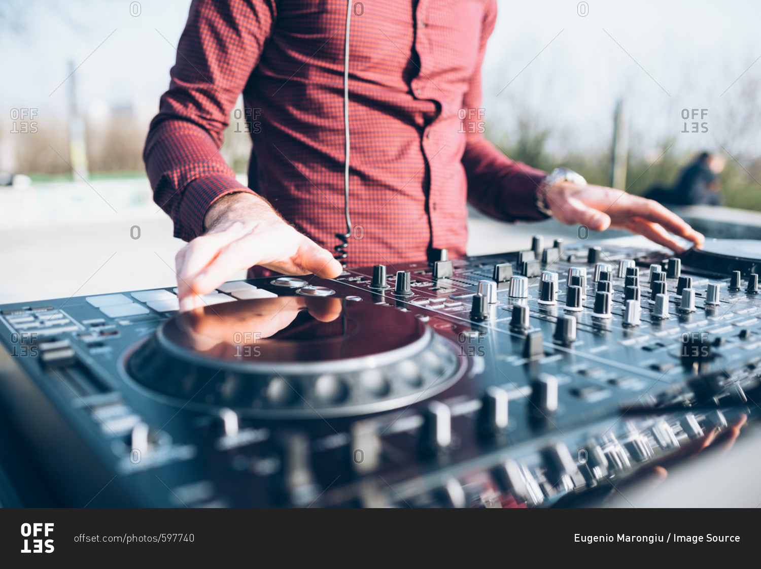 Young man using mixing desk at roof party, mid section, close-up
