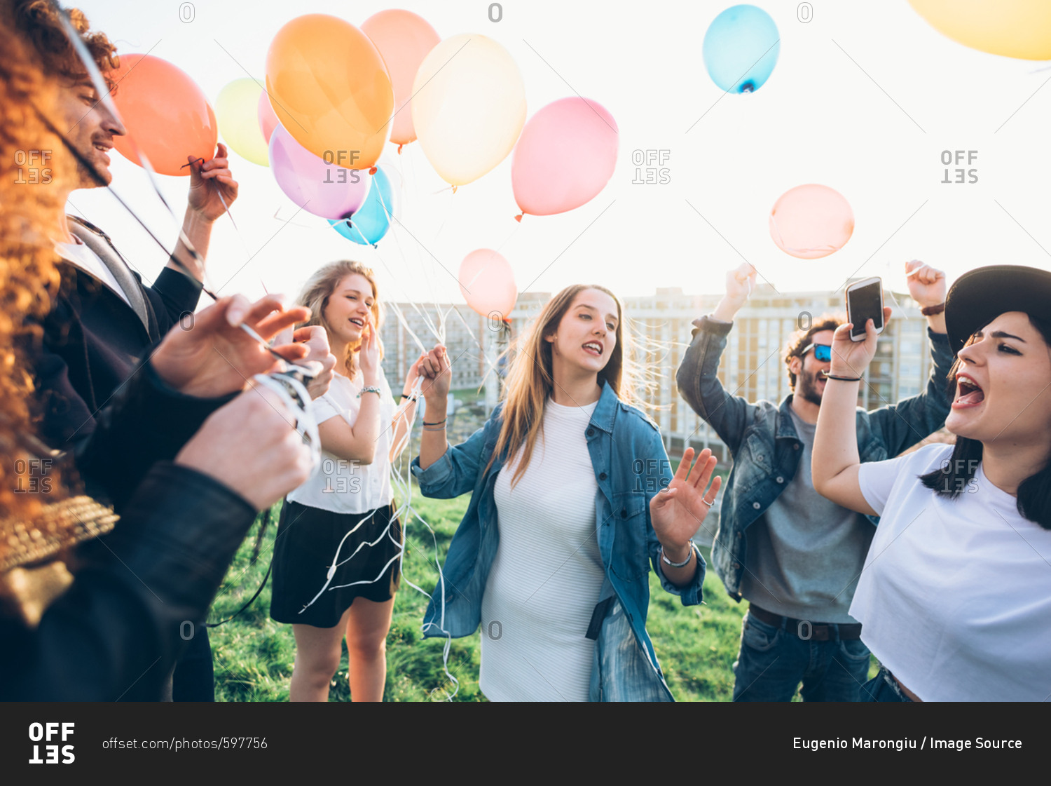 Group of friends enjoying roof party, holding helium balloons