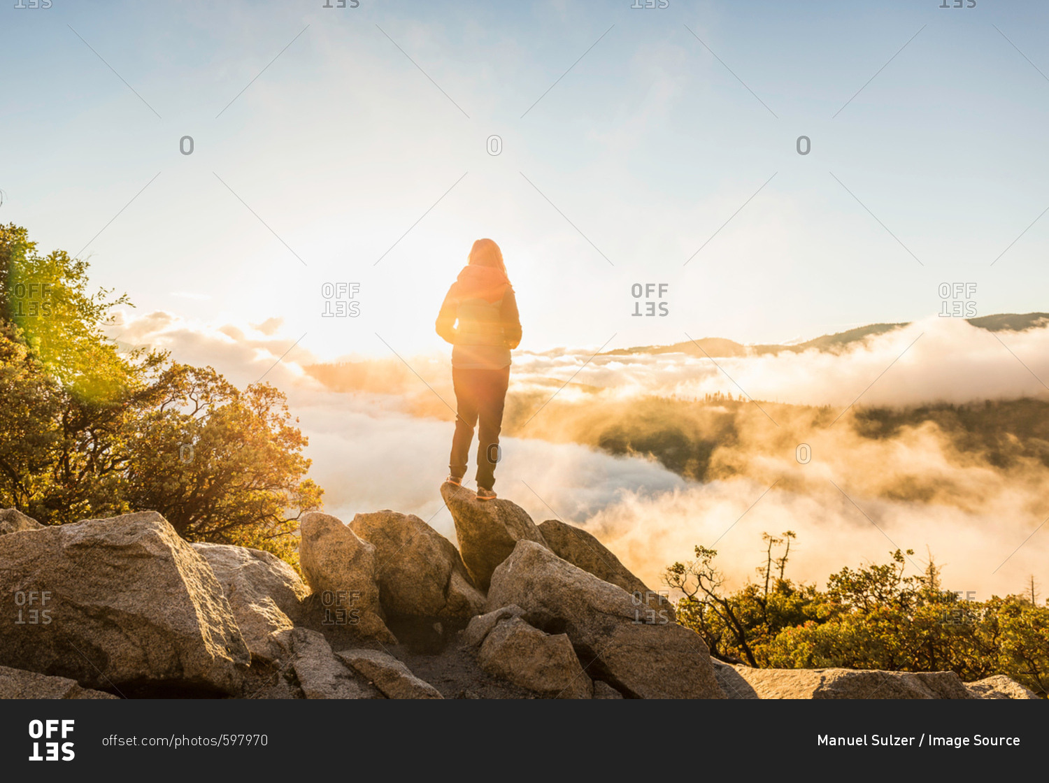 Rear view of woman looking out over valley mist at sunrise, Yosemite National Park, California, USA