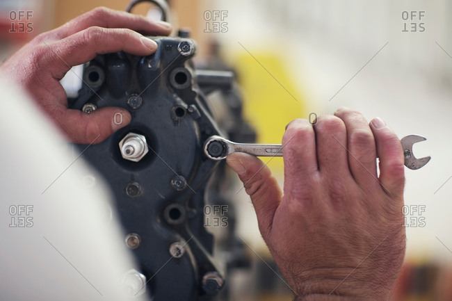 Close up of male hands repairing outboard motor in boat repair workshop