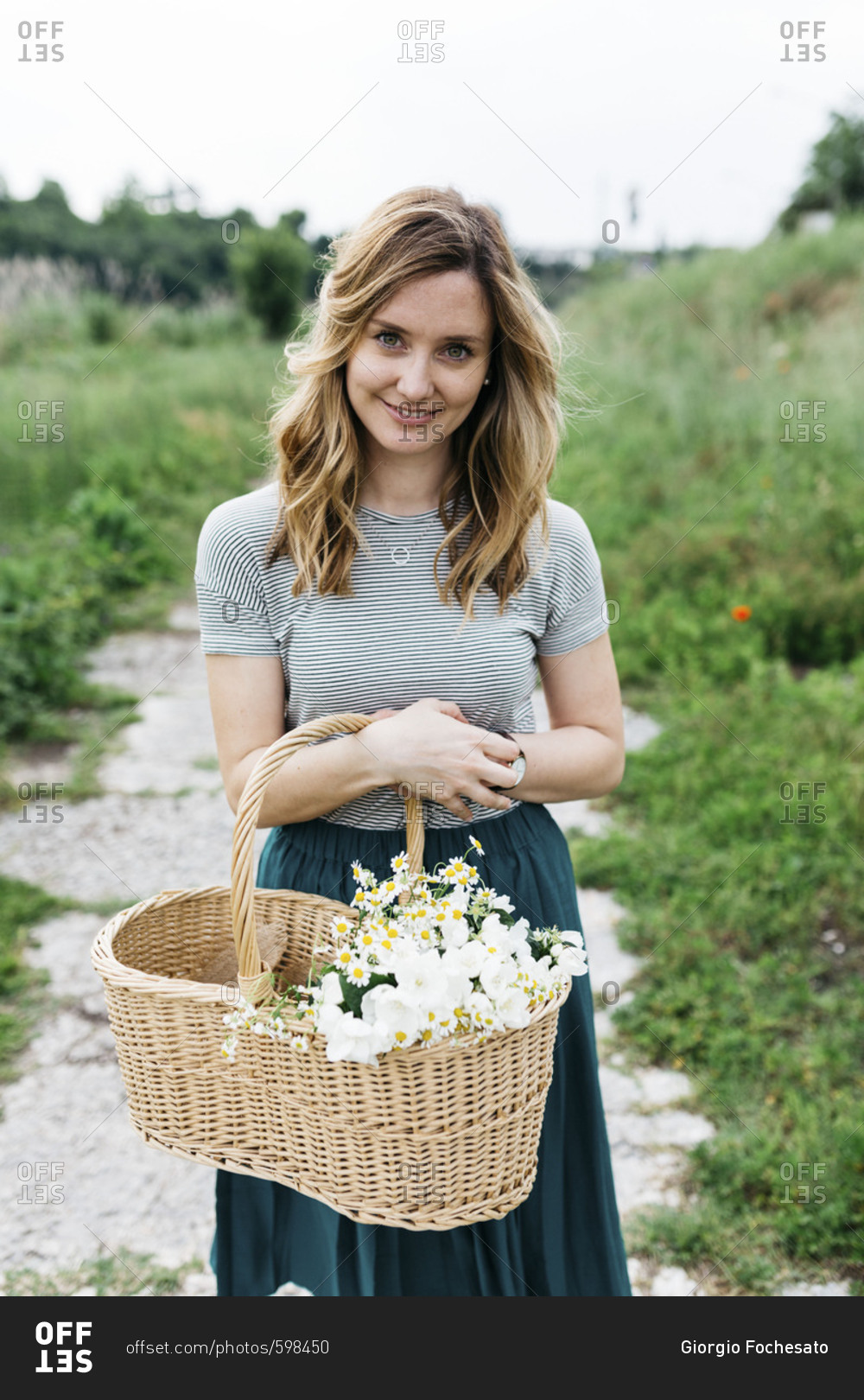 Woman holding basket of flowers in Italian countryside
