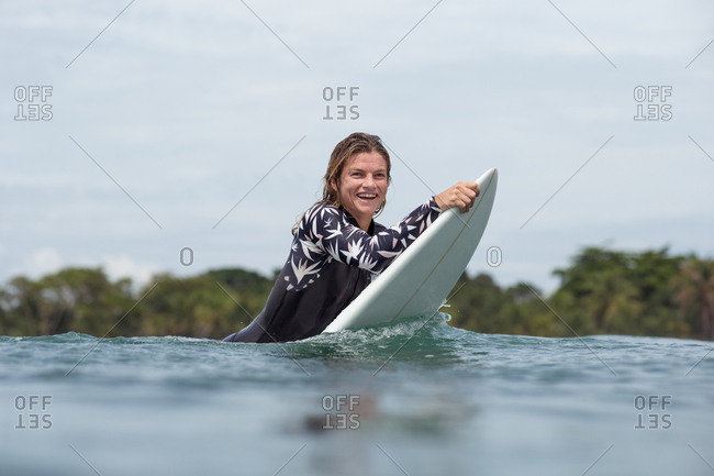 Smiling woman holding surfboard in the water on the tropical coast of Panama