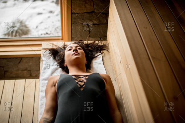 Woman lying down and relaxing in sauna