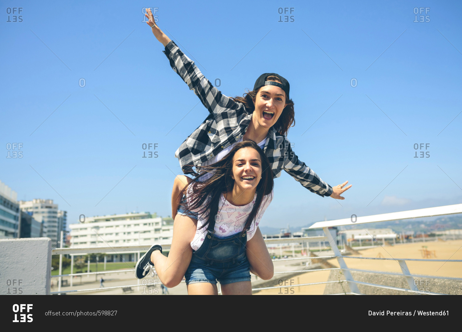 Girl giving her friend a piggyback ride stock photo