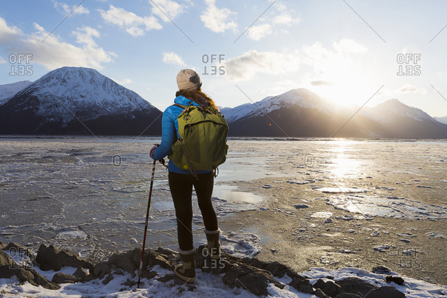 Young woman watching the setting winter sun while overlooking ice flows