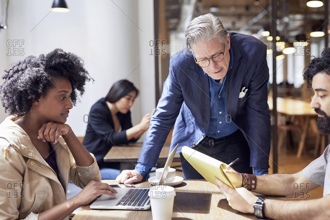 Business people working with female colleague sitting in background