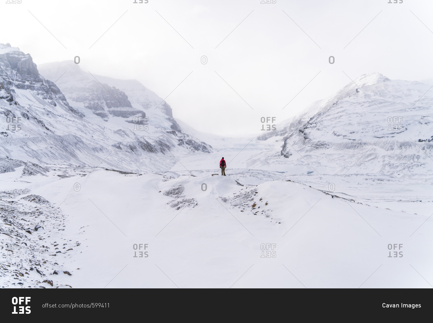 Mid distance view of hiker standing on snow covered landscape during foggy weather