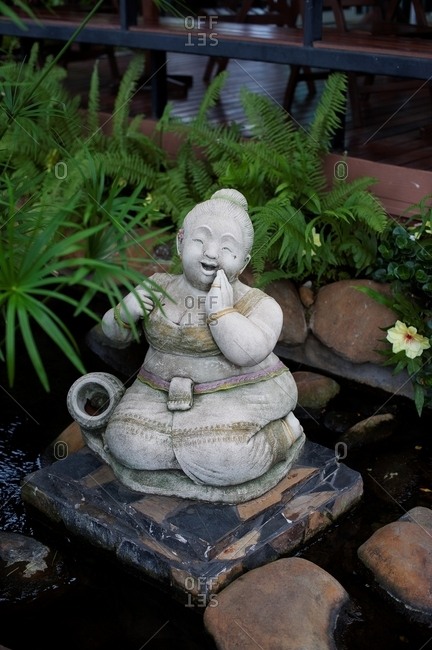 Statue of a woman kneeling and laughing in a garden fountain