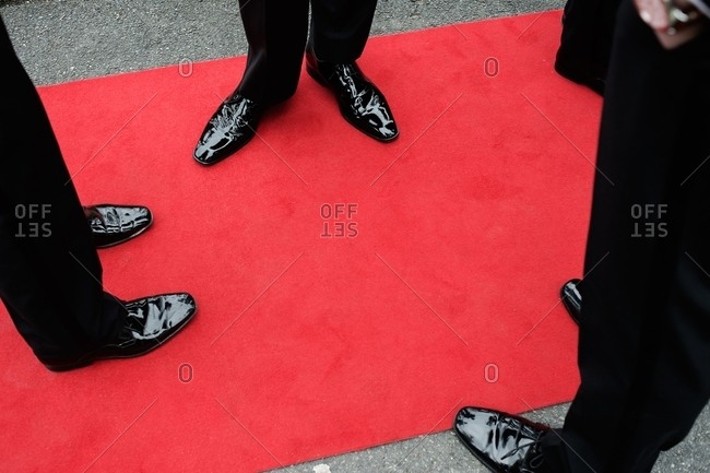 Men in shiny black shoes standing on a red carpet