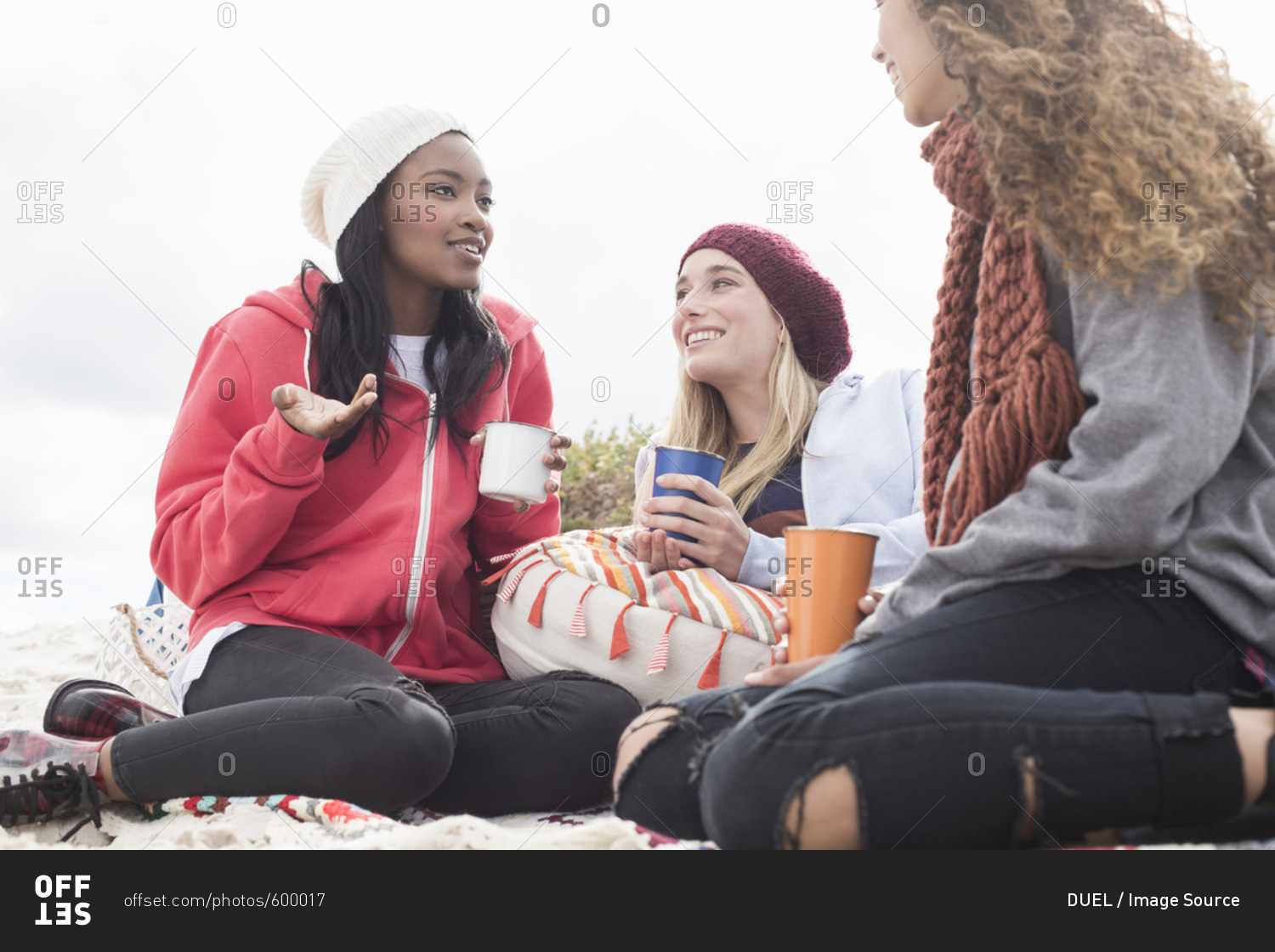 Three young women chatting on beach picnic, Western Cape, South Africa