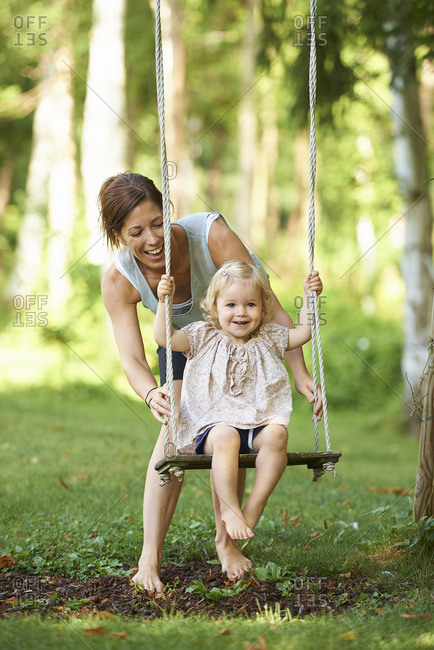 Mid Adult Mother Pushing Toddler Daughter On Garden Swing Stock Photo Offset