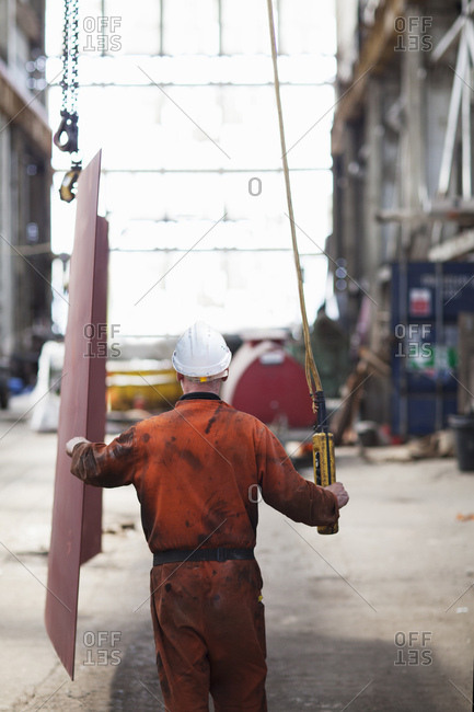 Rear view of worker using winch in shipyard workshop