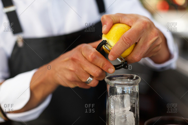 Bartender peeling strip of lemon rind for drink