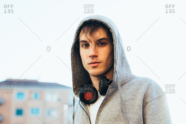Portrait of man wearing hooded top and headphones looking at camera