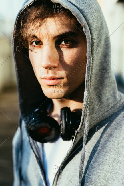 Portrait of man wearing hooded top and headphones looking at camera