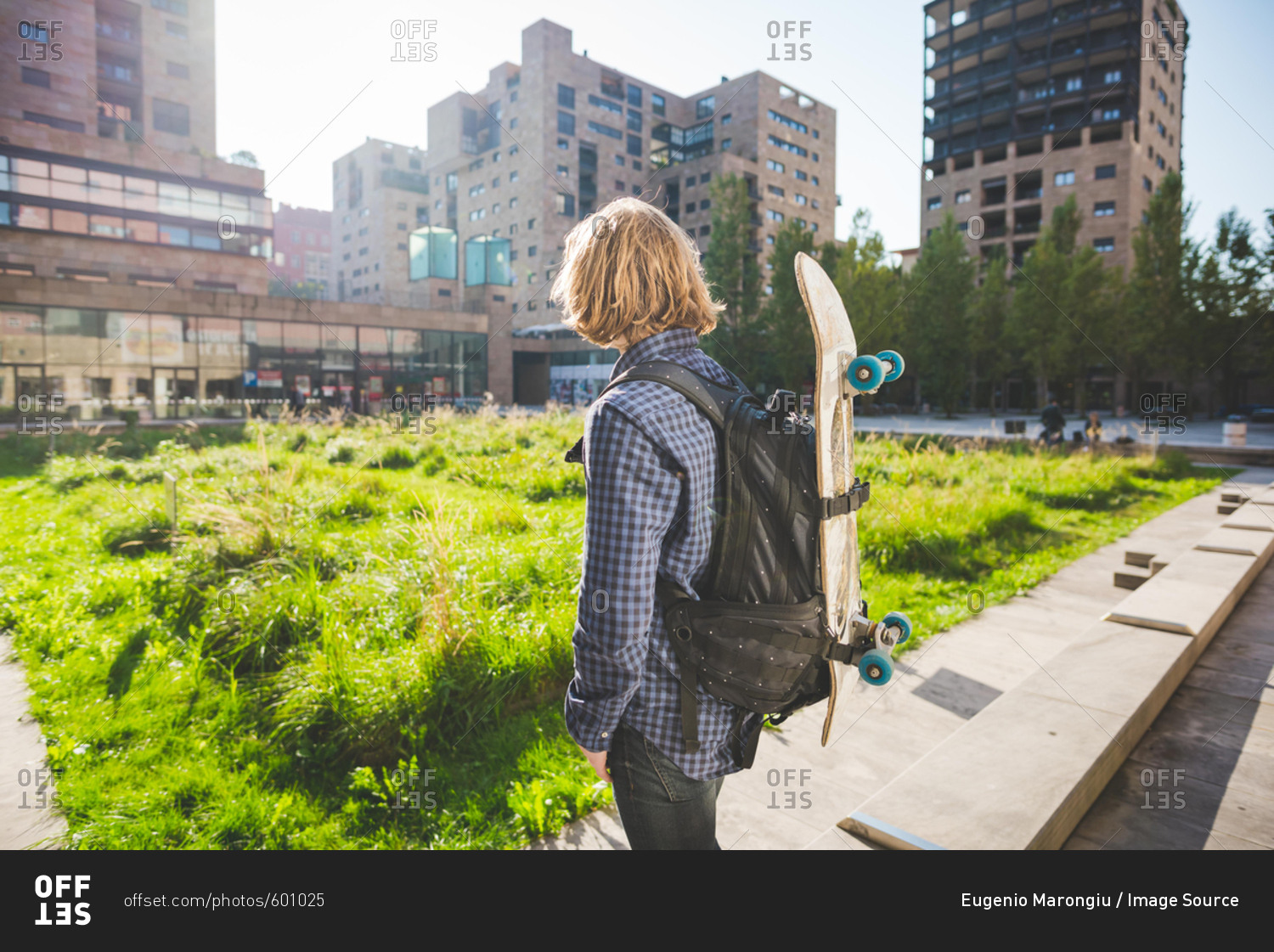 Young male urban skateboarder carrying backpack with skateboard