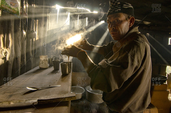 Chaubas, Bagmati District, Nepal - March 31, 2012: Sunlight Filters Through Smoke As A Man Brews Nepali Tea In His Small Teahouse In Nepal