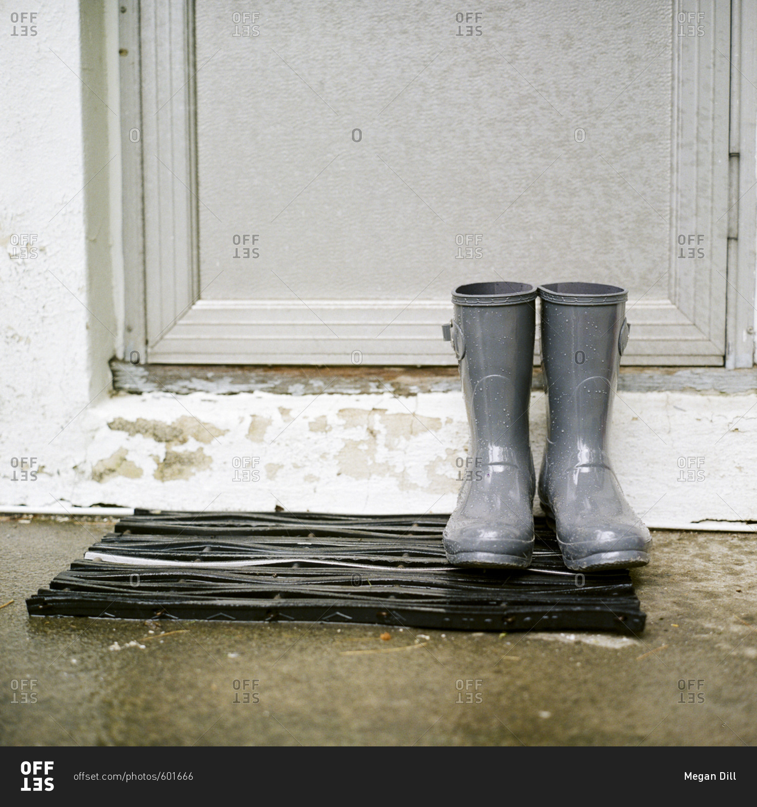 Gray rain boots on a mat by a door