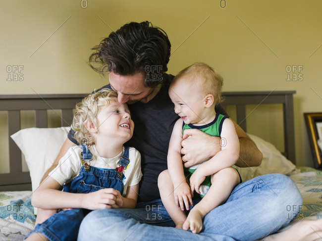 Father kissing sons (12-17 months, 4-5) in forehead