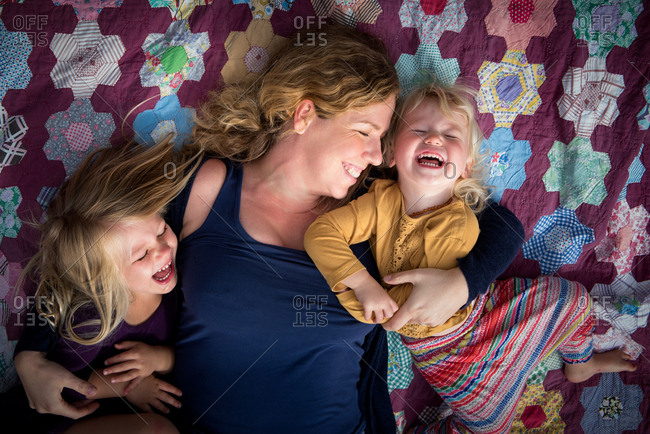Portrait of mother with happy young daughters on quilt