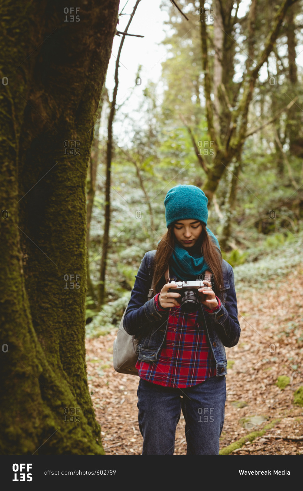 Woman looking clicked photos in vintage camera at forest