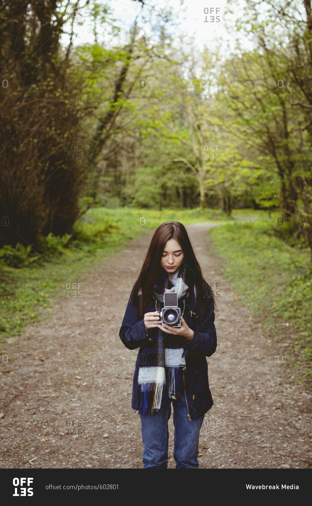 Woman looking clicked photos in vintage camera at forest