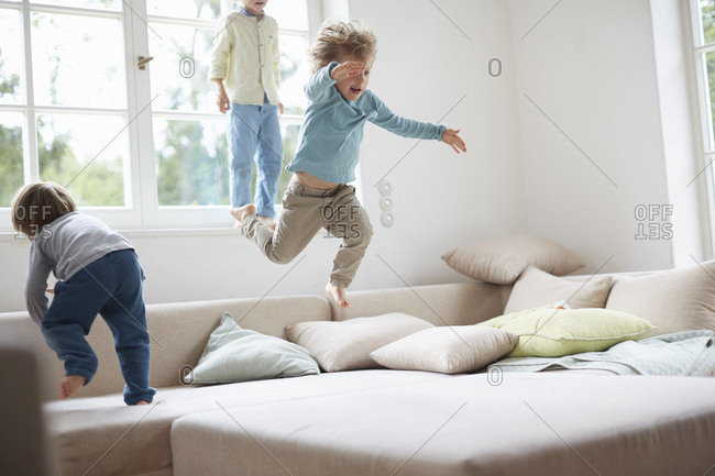 Three young boys jumping on sofa