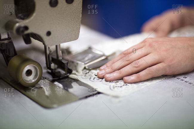 Hands of male textile designer using sewing machine in old textile mill