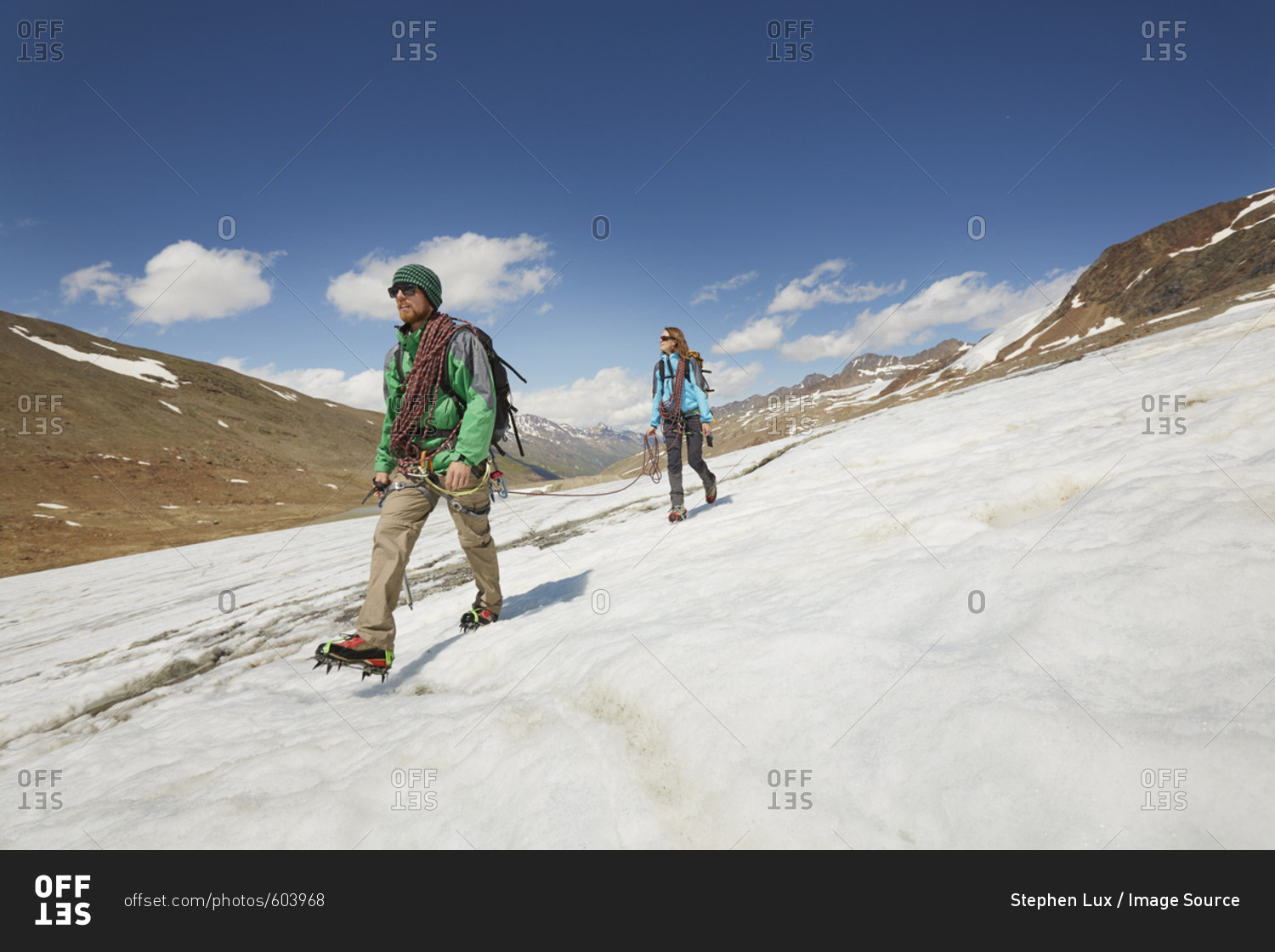 Young couple hiking down ice on Val Senales Glacier, Val Senales, South Tyrol, Italy