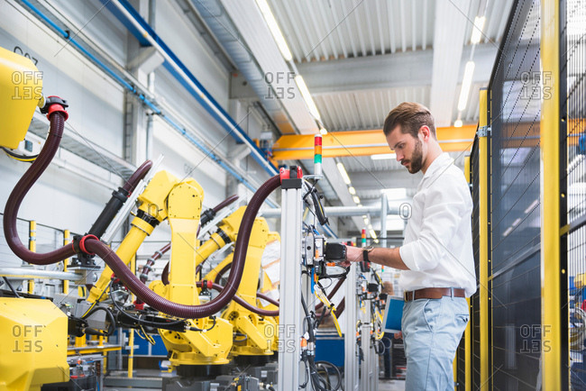 Young male engineer testing machinery in engineering factory