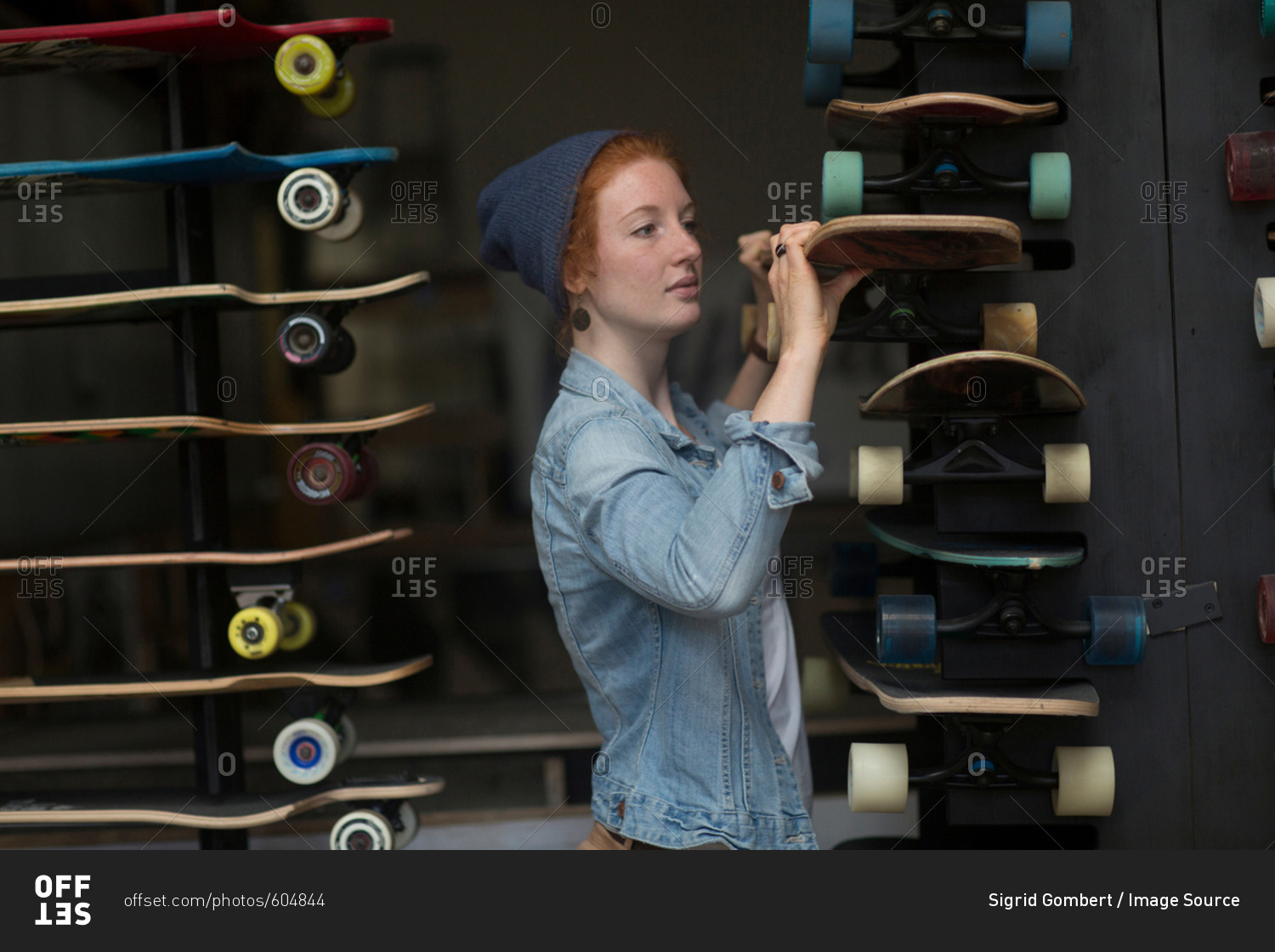 Woman working in skateboard shop, organizing skateboard display