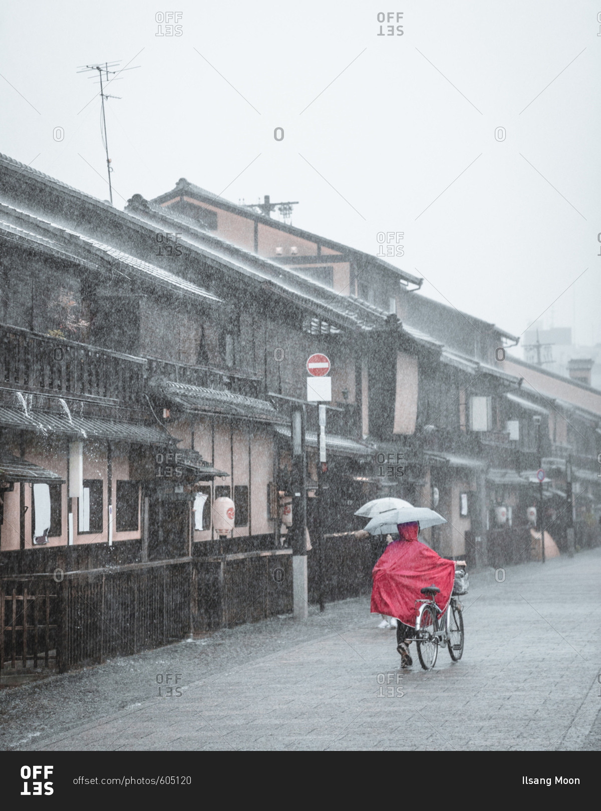 Person walking bike down city street in the rain, Kyoto, Japan