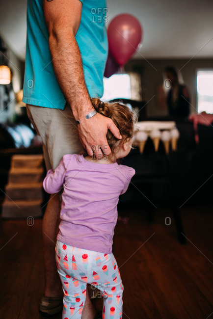 Toddler girl holding onto daddy's leg