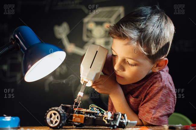 Handy child working on his electronic project with a soldering gun