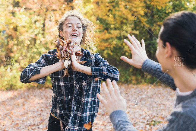 Happy playful woman throwing autumn leaves at boyfriend