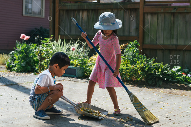 Brother And Sister Sweeping Up Leaves Together On A Patio Stock Photo Offset