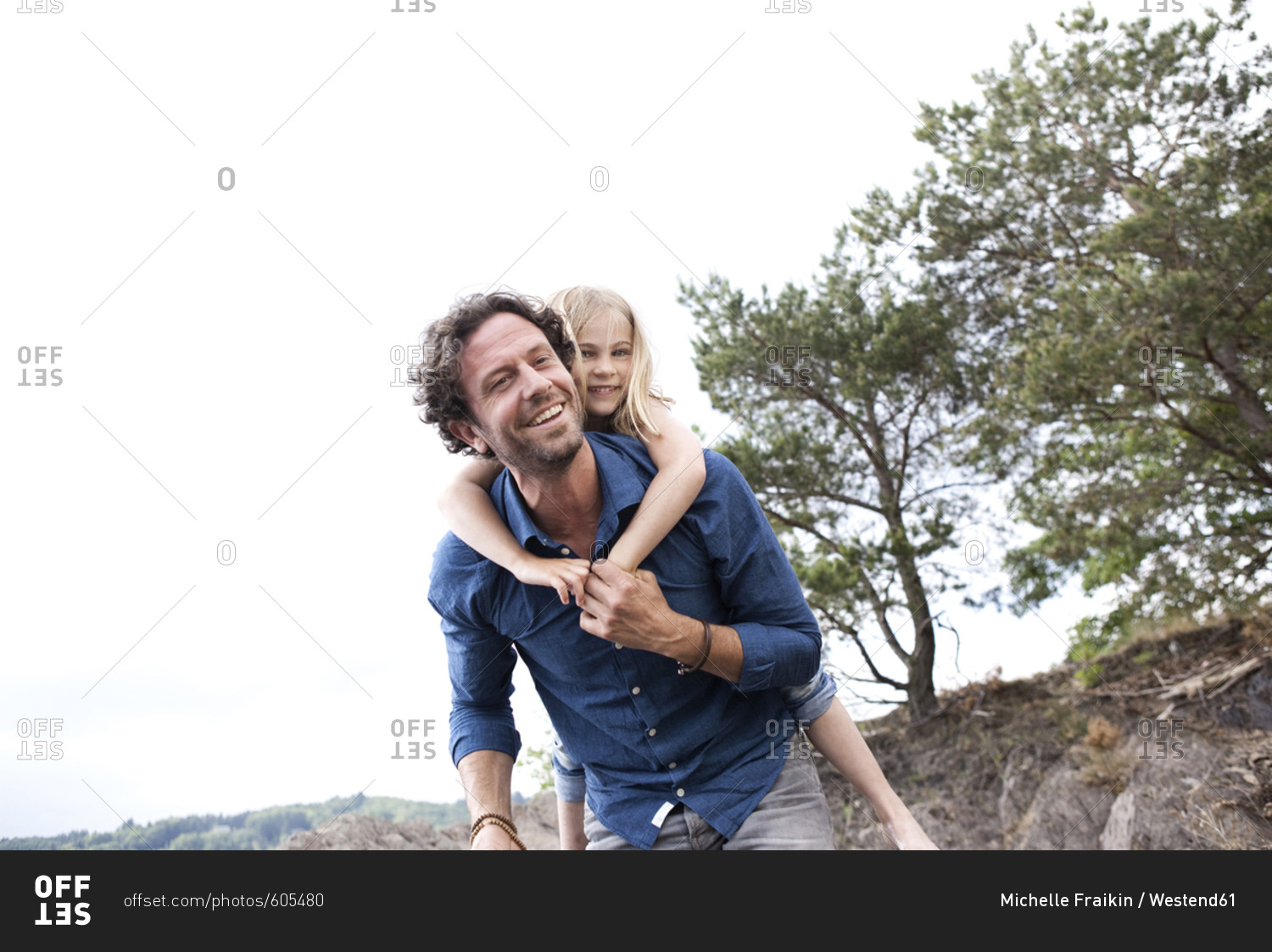 Father carrying happy daughter piggyback stock photo - OFFSET