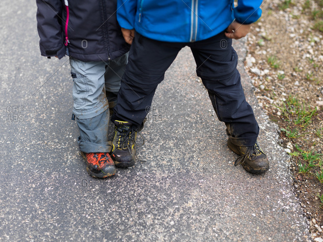 Sister and brother, young girl and boy showing their muddy shoes during a family trail in the French jura