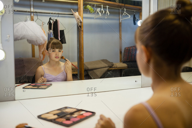 Girl doing make up while sitting in dressing room at backstage