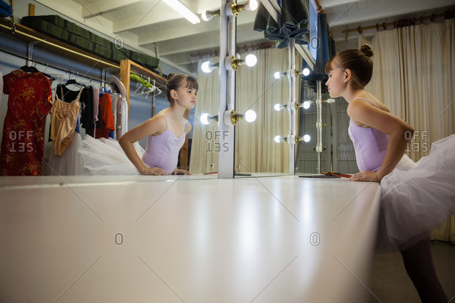 Side view of girl looking in mirror at backstage