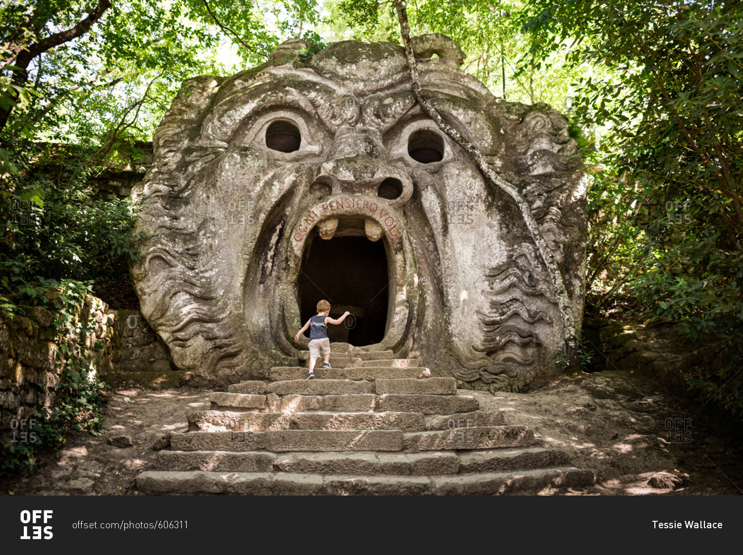 Boy walking into mouth of stone sculpture